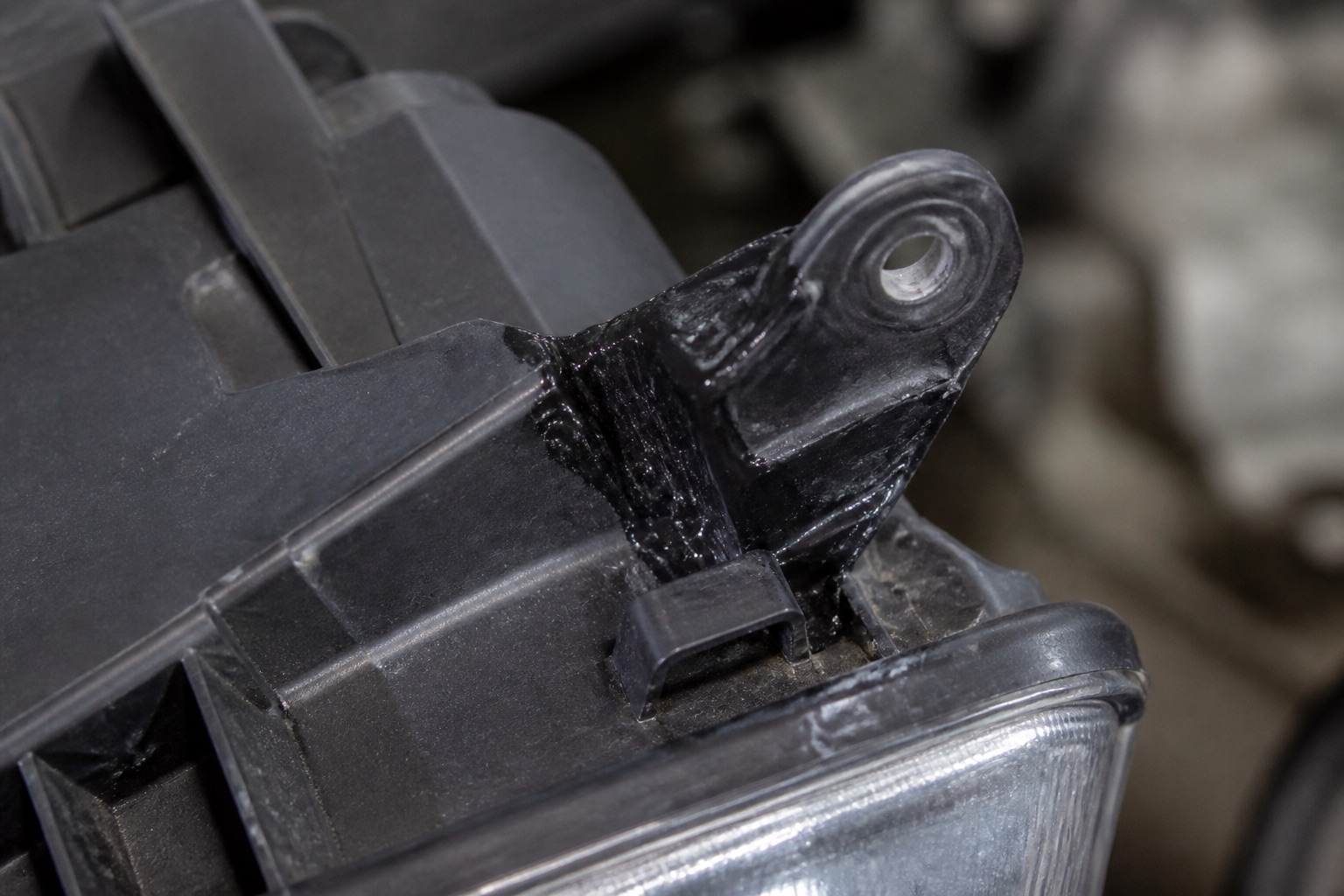 Broken headlight mounting bracket and clip being reinforced